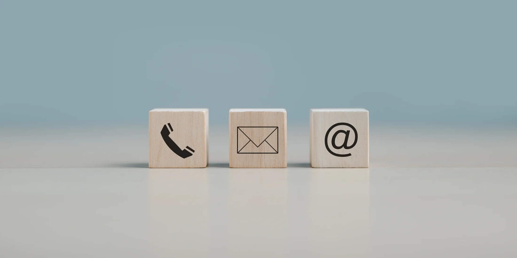 Holzwürfel mit Symbolen für E-Mail, Telefon und Post